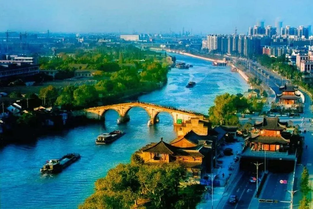 Aerial view of the three-arch Gongchen Bridge over the Grand Canal with barges and Hangzhou rooftops