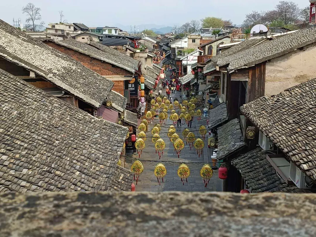 Grey-tile rooftops over the flagstone main street of Qingyan, hung with rows of yellow lanterns