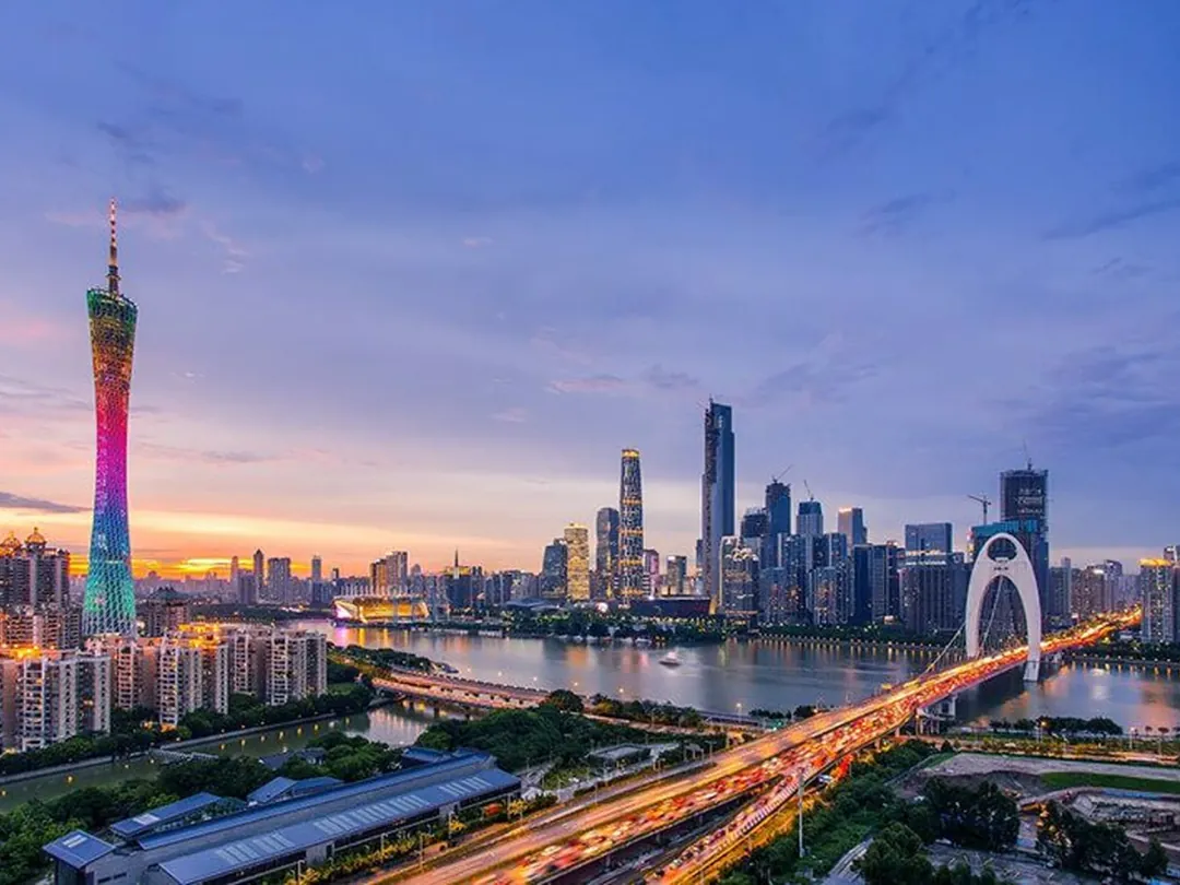 Guangzhou at dusk: Canton Tower lit rainbow over the Pearl River, the Zhujiang New Town skyline and the Liede Bridge trail-lit on the right