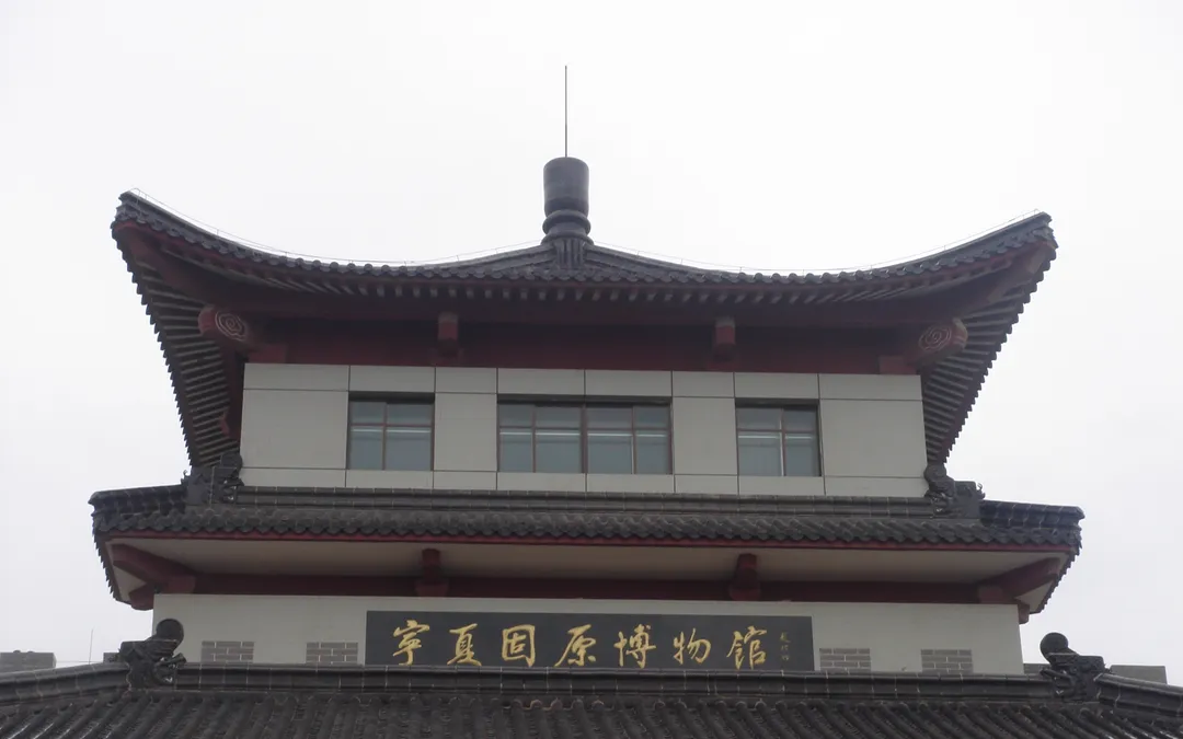 The upper storey of the Guyuan Museum in Ningxia: grey tiled roofs and a gold-lettered plaque reading 'Ningxia Guyuan Museum'