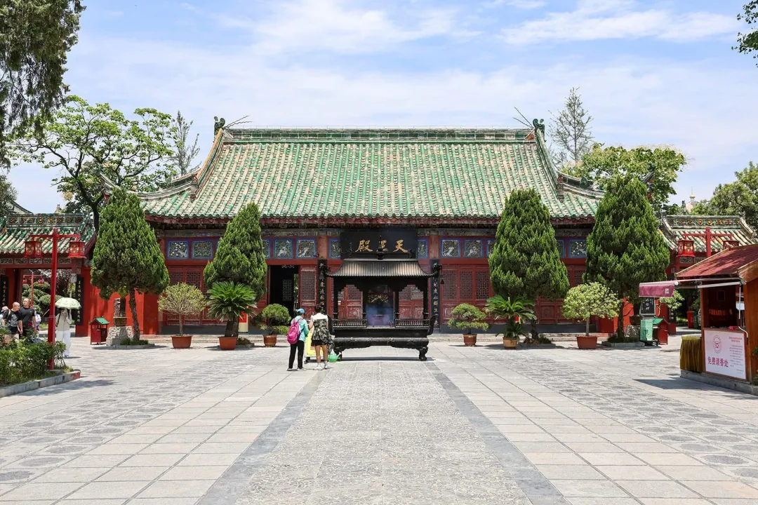The Heavenly Kings Hall of Daxiangguo Temple in Kaifeng, green-glazed roof and red walls around a censer-filled courtyard