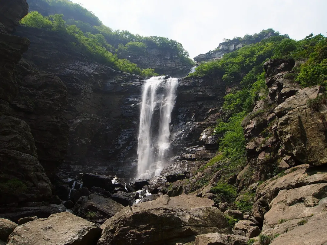 The Three-Step Waterfall dropping through a rock gorge, the main fall split by ledges, boulders and green slopes around it