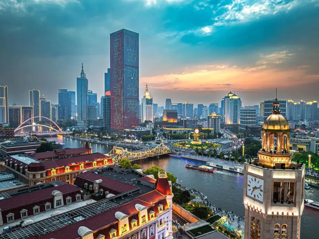 Dusk on the Hai River in Tianjin: red-roofed European buildings, Jiefang Bridge and a domed clock tower against the lit skyline
