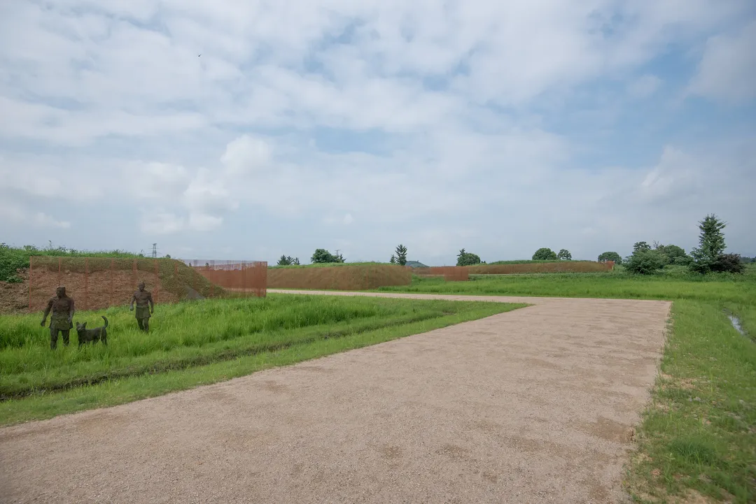 Grassy rampart reconstructions and bronze figures at the Liangzhu archaeological park in Yuhang
